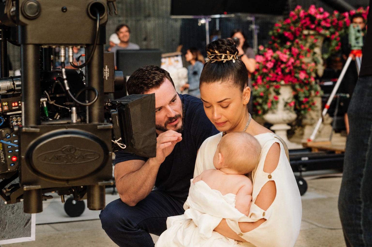 A director beside the camera working with a performer holding a baby
