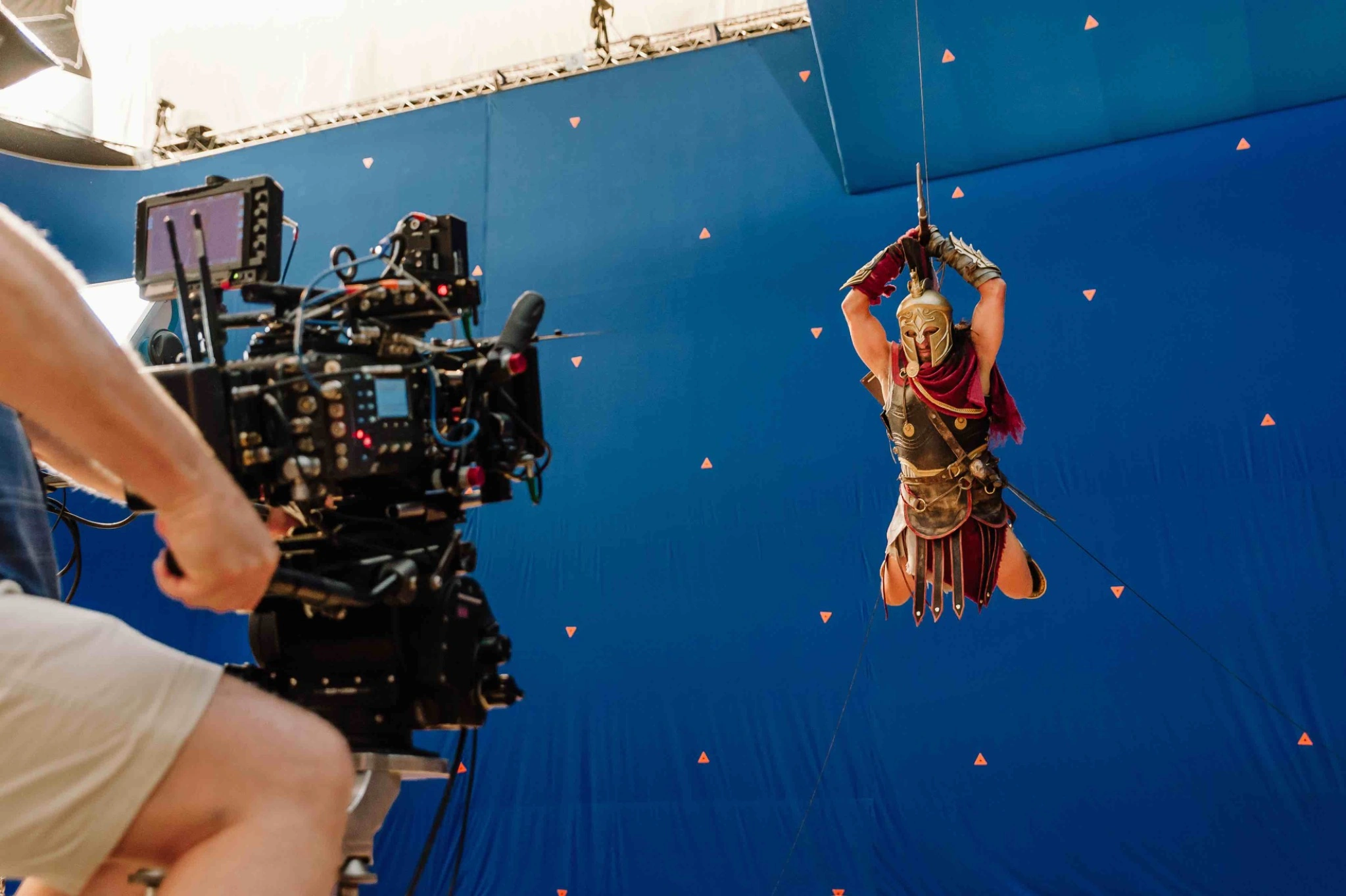 A camera crew filming a suspended performer against a blue screen